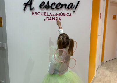 Niña señalando el logo de A Escena Escuela de Música y Danza