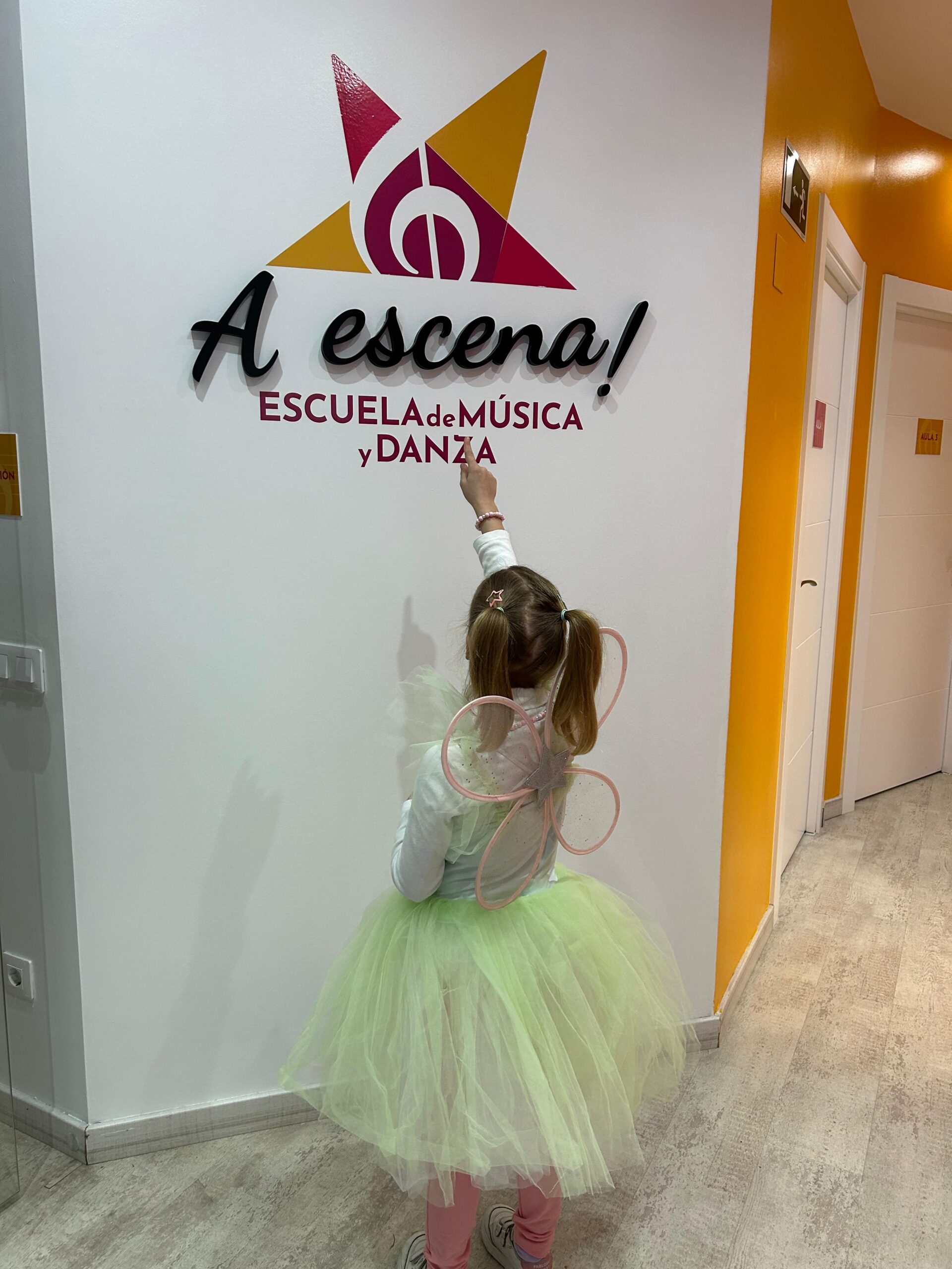 Niña señalando el logo de A Escena Escuela de Música y Danza
